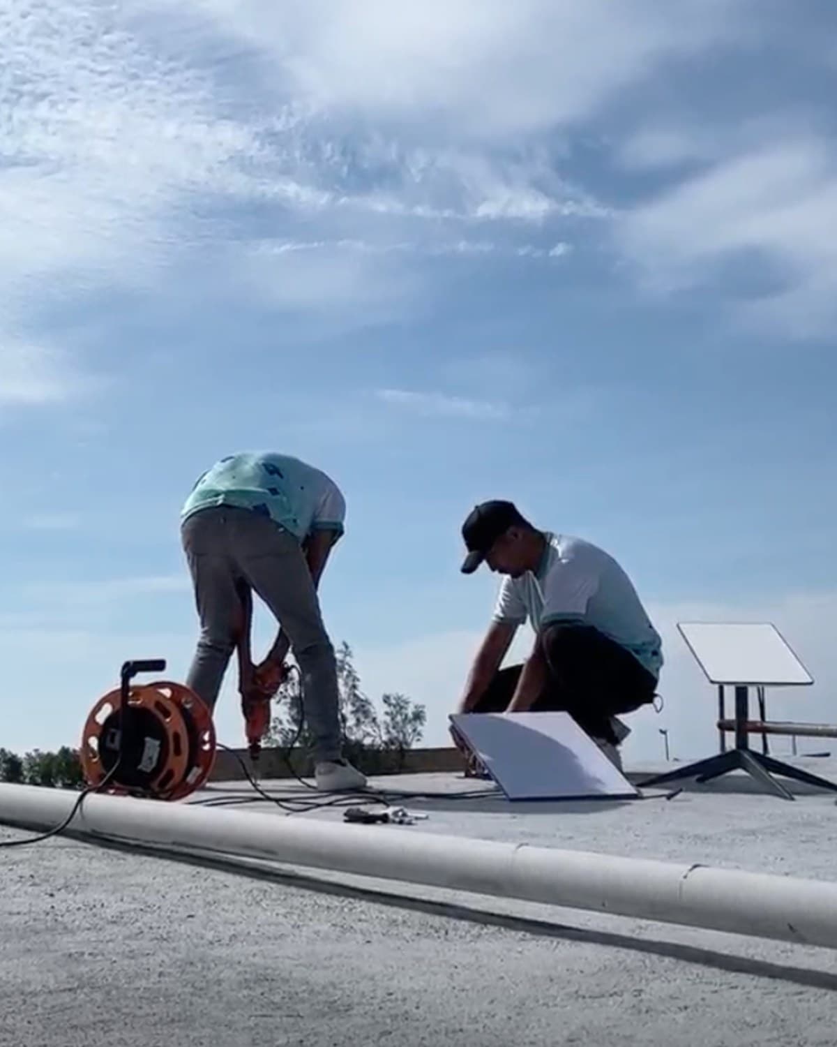 TechCare crew installing a Starlink dish on a rooftop, drilling the mount with the dish staged beside them