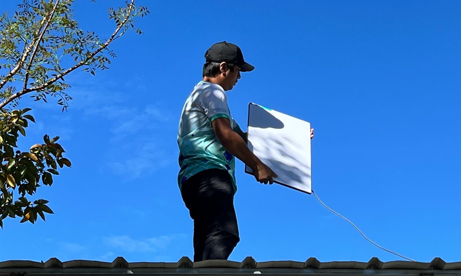 TechCare technician carrying a Starlink dish across a rooftop during an install